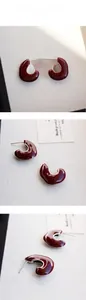 Gros plan de boucles d'oreilles émaillées bordeaux en forme de C avec monture en métal argenté
