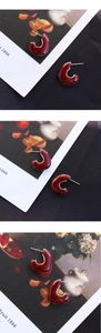 Détails macro des boucles d'oreilles émaillées rouge bordeaux en forme de C rétro