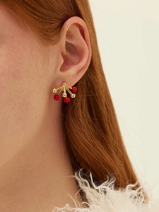 Close-up of a model wearing red enamel firework stud earrings with gold metal beads