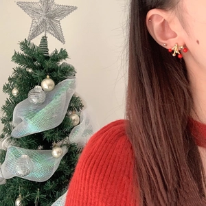Detail of gold fireworks stud earrings with red beads worn by a model in holiday setting