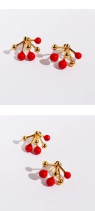 Detailed view of red enamel bead earrings with gold-tone radial burst stud structure