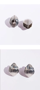 Détail de boucles d'oreilles argentées à texture coquillage avec nervures géométriques