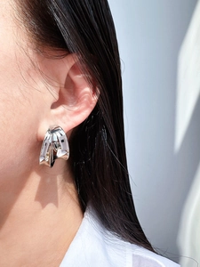 Close-up of polished silver geometric layered C-shape hoop earrings on a model