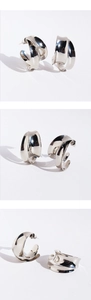 Close-up of silver wide C-shape earrings with layered irregular cross metal design