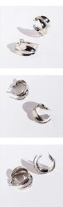 Macro detail of silver layered irregular C-shape wide hoop earrings with mirror finish