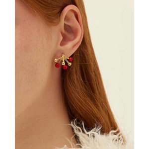 Golden stud earrings with red enamel bead starburst design shown on a female model