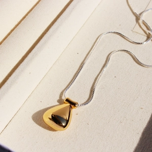 Vintage silver snake chain necklace with a polished gold teardrop bottle pendant detail