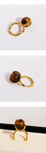 Détail macro d'une bague dorée vintage avec pierre œil de tigre sphérique et texture lave