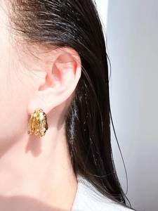 Detail von goldenen Lava-Struktur-Ohrringen getragen von Model mit Hochglanz-Finish