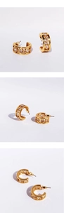 Macro detail of golden C-shaped hoop earrings with heart-cut zircon and hollow patterns