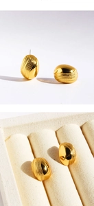 Nahaufnahme goldener Wellen-Ohrstecker mit Spiraltextur und polierter Spiegeloberfläche