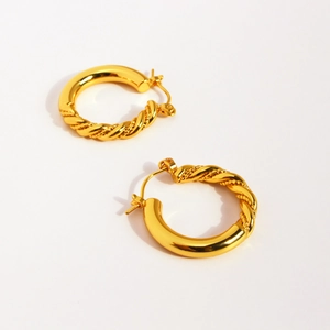 Classic gold twisted hoop earrings with a mix of smooth and rope textures on a white background