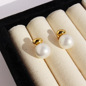 Elegant gold bead and pearl stud earrings displayed on a premium jewelry box insert