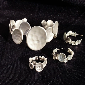 Macro shot of silver jewelry set with irregular hammered metal discs on dark velvet