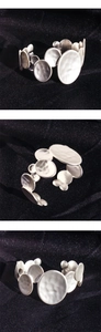 Close-up of matte silver irregular circular plates with hammered texture on C-shaped cuff