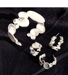 Macro shot of silver hammered metal jewelry set including cuff, ring and earrings