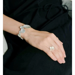 Close-up of minimalist silver irregular oval pebble-shaped bracelet and ring set