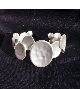 Close-up of matte silver open bangle featuring irregular overlapping hammered round discs
