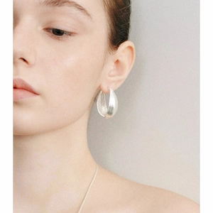 Gros plan de boucles d'oreilles minimalistes en argent brossé en forme de goutte d'eau