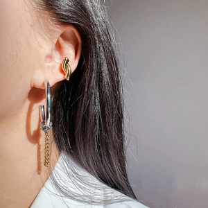Detail of silver hoop earring with gold chain tassel and knot ear cuff on model