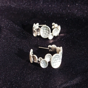 Textured silver C-shaped earrings with hammered metal discs and vintage finish