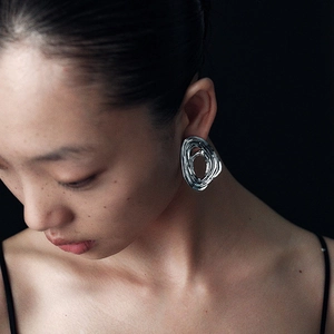 Artistic silver swirl wave earrings with irregular liquid metal texture on female model