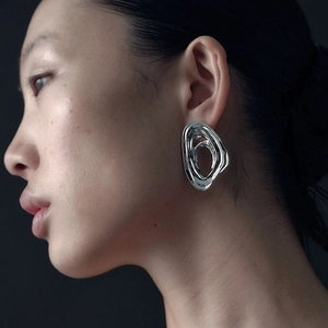 Artistic silver irregular flowing earrings worn by model on minimalist dark background