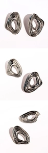 Macro detail of silver liquid metal earrings showing irregular layered vortex wave texture