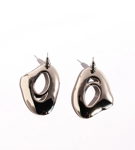 Close-up of silver irregular swirling hollow earrings with polished fluid metal texture