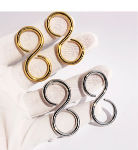 Macro shot of minimalist figure-eight gold and silver earrings with smooth polished finish