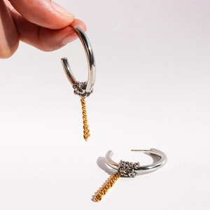 Two-tone C-shape hoop earrings with silver knot and gold chain drop detail