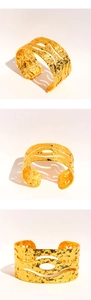 Macro detail of wide gold metal cuff bracelet with hammered texture and wavy cutouts