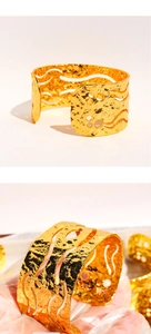 Detail of wide gold cuff bracelet featuring hammered texture and hollow-out wavy design