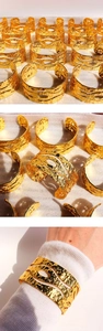 Macro shot of hammered metal texture and hollow oval cutouts on the wide gold bangle