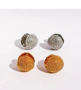 Détail macro des créoles boules dorées et argentées avec texture métallique tressée