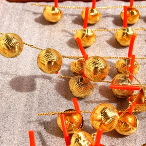 Macro shot of golden textured metal sphere earrings with geometric woven patterns