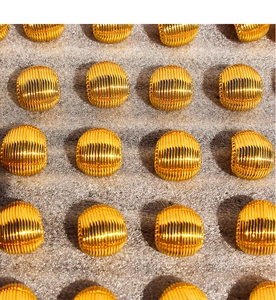 Detailed view of golden oval earrings with vertical stripes and small bead edges