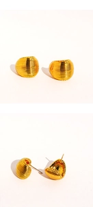Macro shot of gold spherical stud earrings featuring shell-like wave texture and hollow back
