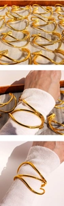 Macro detail of golden multi-layer wave hollow open cuff bracelet with mirror finish