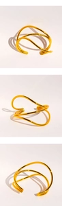 Macro shot of polished gold layered wavy cuff bracelet with geometric shadows