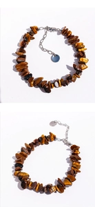 Makroaufnahme der unregelmäßigen Tigerauge-Steine und der silbernen Verlängerungskette am Armband
