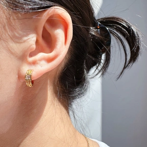 Close-up of gold-plated twisted hoop earring with square zircon inlay on ear