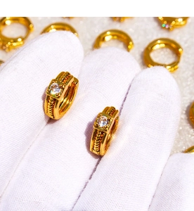 Macro detail of gold-plated twist earrings featuring a square cubic zirconia stone inlay