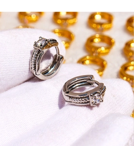 Macro shot of silver twisted hoop earrings featuring square-cut white zircon settings