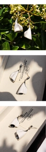 Detail of white enamel calla lily drop earrings with silver trim and curved petals