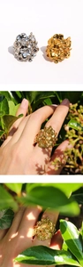 Dettaglio di eleganti anelli floreali in oro e argento con petali traforati fini