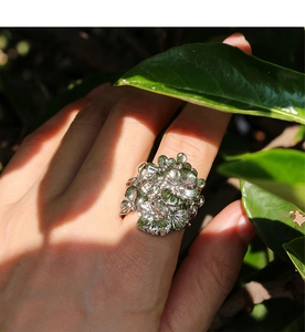 Dettaglio dell'anello largo traforato in argento con fiori indossato alla luce naturale