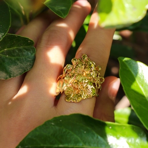 Anello largo traforato in oro con petali a strati in un ambiente naturale esterno