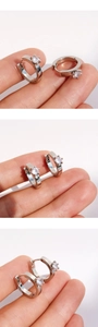 Close-up of silver huggie earrings featuring a six-prong round cubic zirconia setting