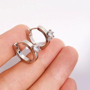 Handheld view of silver huggie earrings with a single sparkling cubic zirconia stone